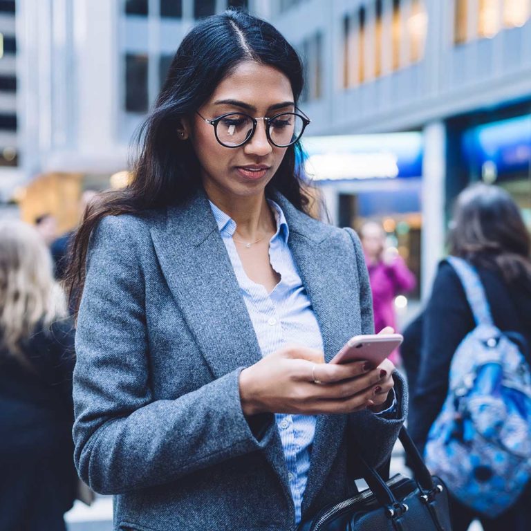 Woman texting in busy street Canadian Immigration Lawyers